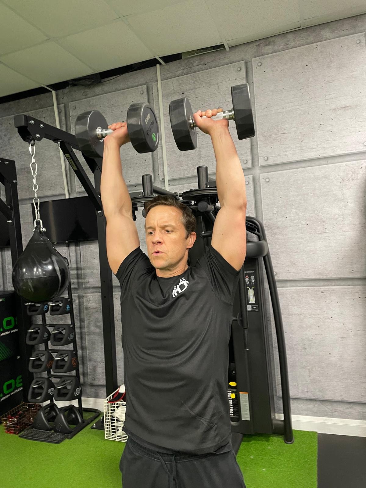 Dumbbell shoulder press representing strength training within The Foundations